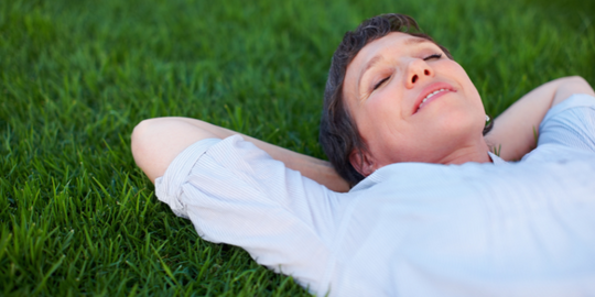 Menopausal woman lying in grass